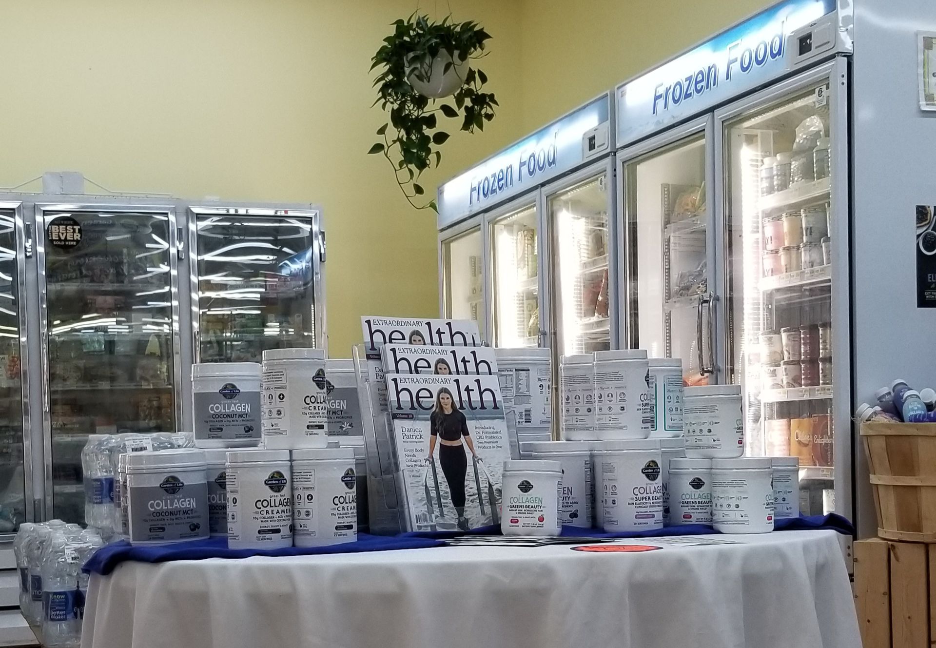 A table displaying yogurt and promotional materials in front of refrigerated cases.