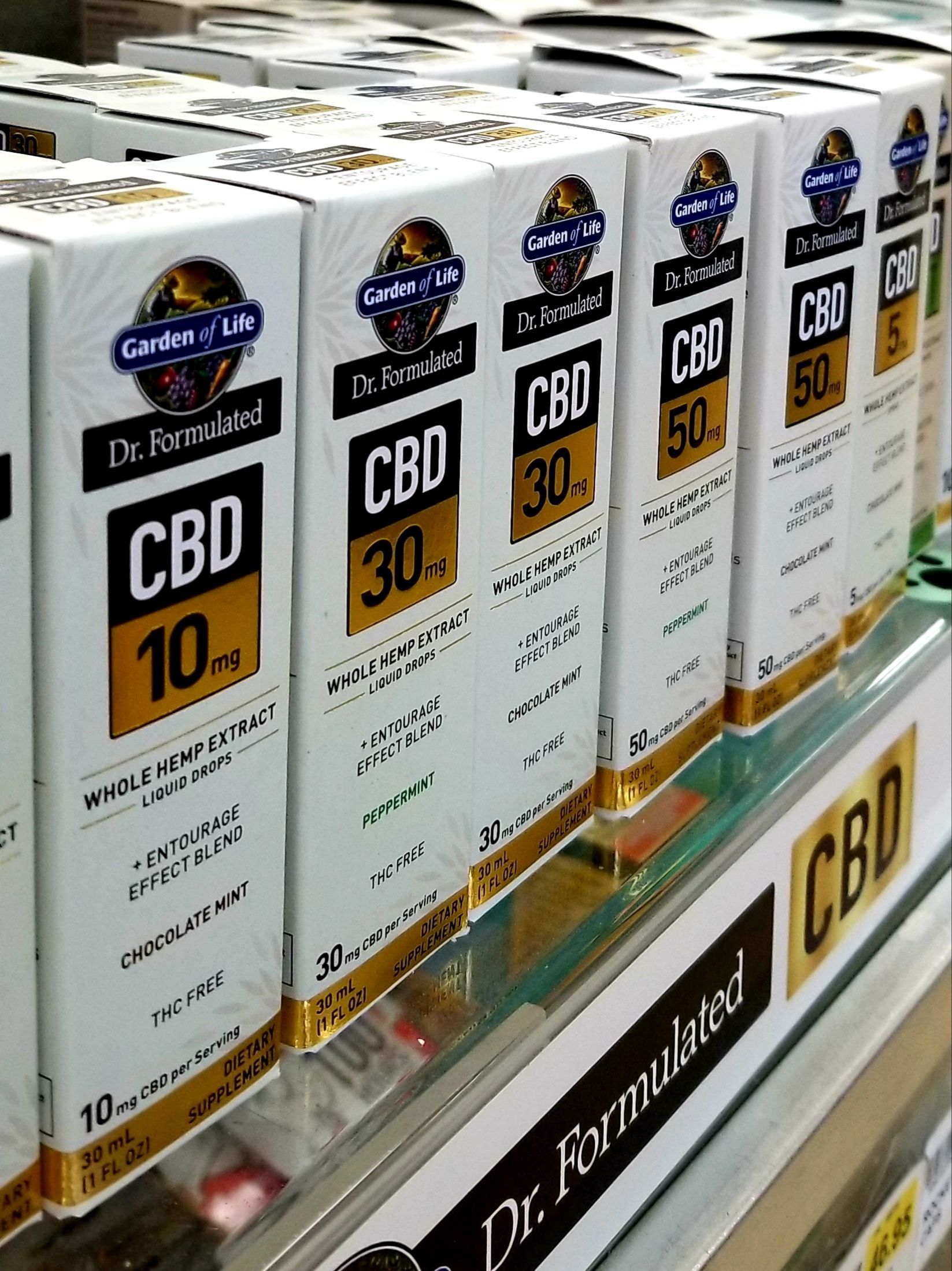 Boxes of CBD products in a store. Labels indicate dosage: 10mg, 30mg, and 50mg, 
