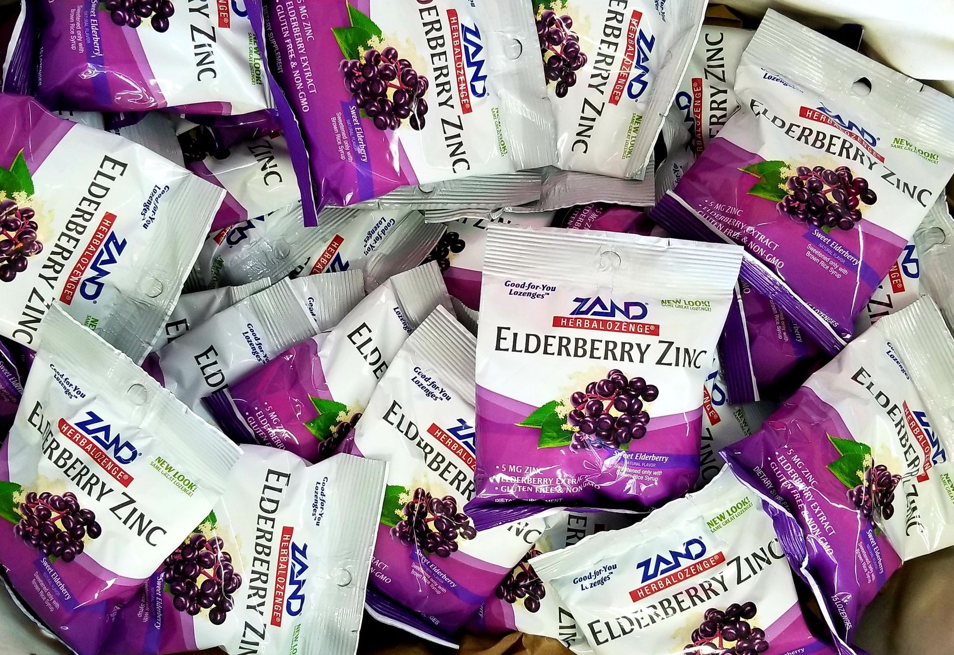 Pile of Zand Elderberry Zinc packets, purple and white packaging.