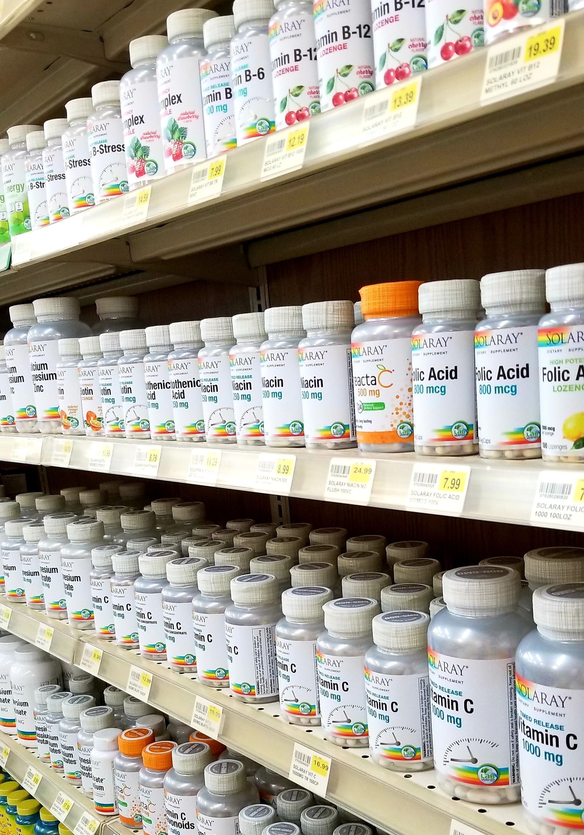 Shelves stocked with various vitamin bottles in a brightly lit store.