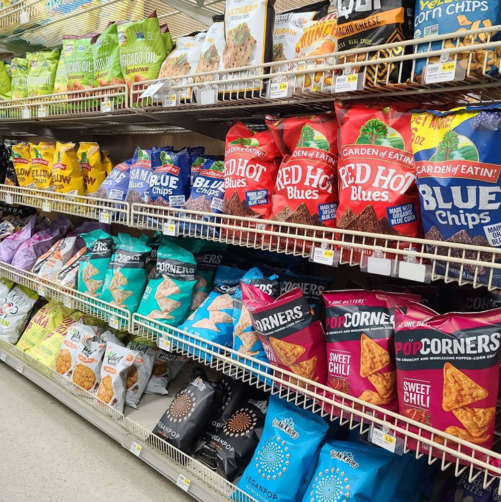 Shelves stocked with various brands of chips in a grocery store.