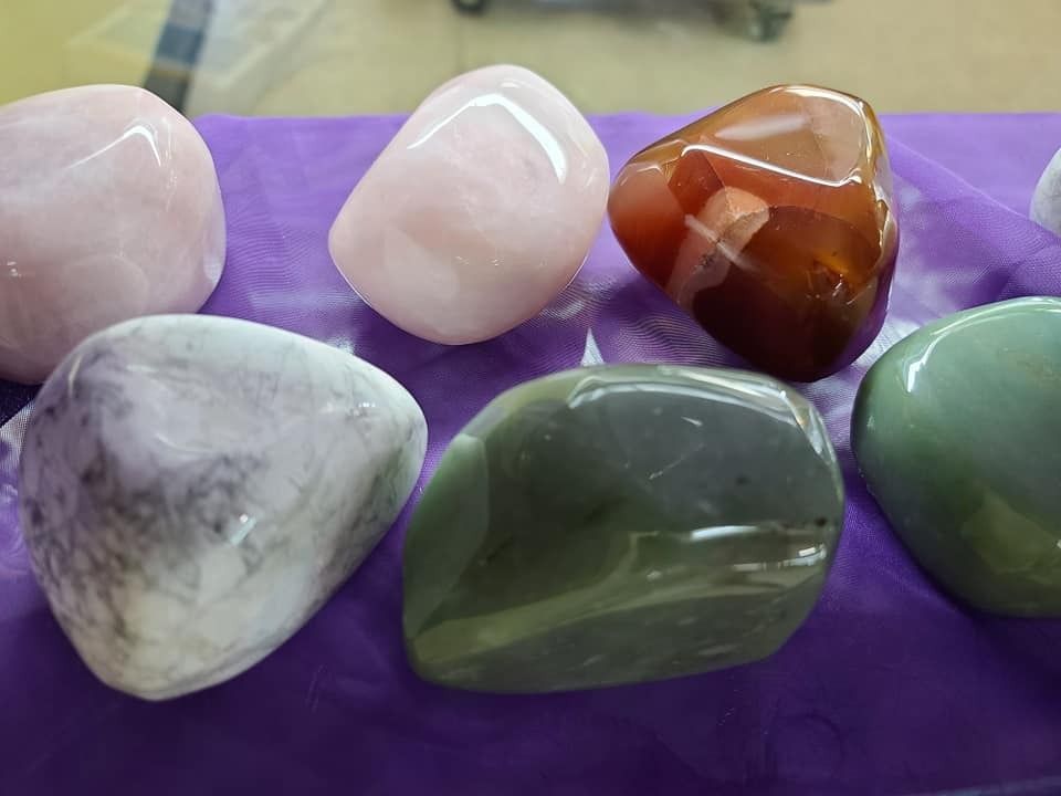 Polished gemstones in pink, brown, green, and gray on a purple surface.