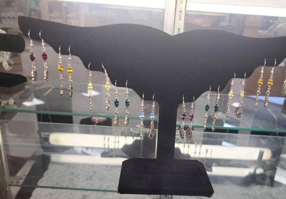 Black earring display with colorful dangling earrings in a glass case.