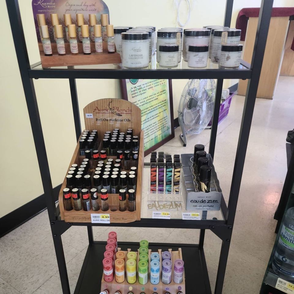 Shelving unit displaying various aromatherapy products, including roller bottles, candles, and essential oils in a retail setting.