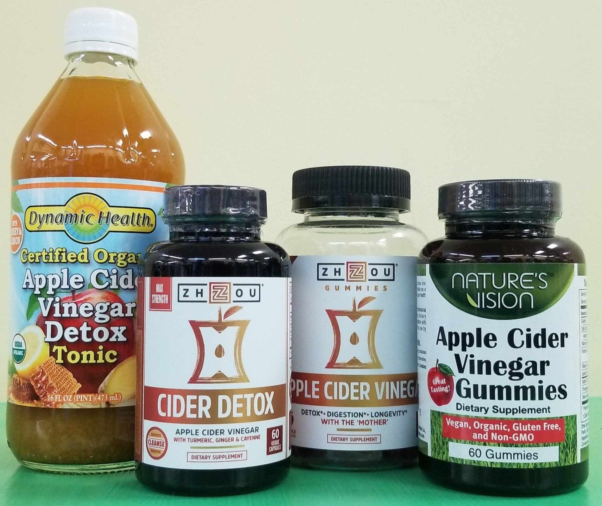 Bottles of apple cider vinegar products, including a tonic and gummies, with various labels.