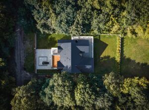 An aerial view of a house in the middle of a forest.
