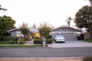A white car is parked in front of a house