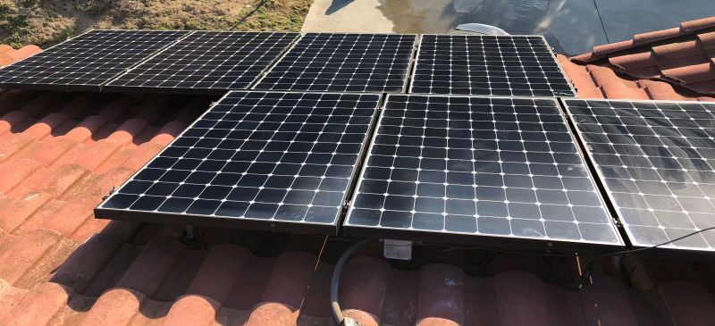 A row of solar panels sitting on top of a tiled roof.