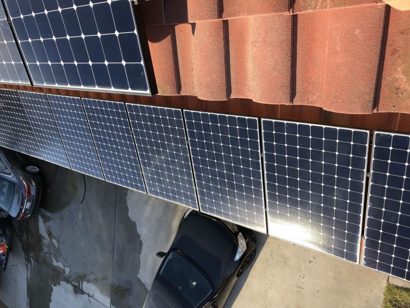 A car is parked under a row of solar panels