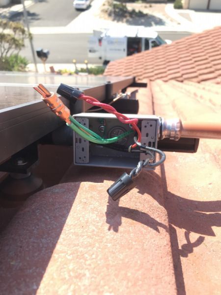 A bunch of wires are connected to a box on a roof