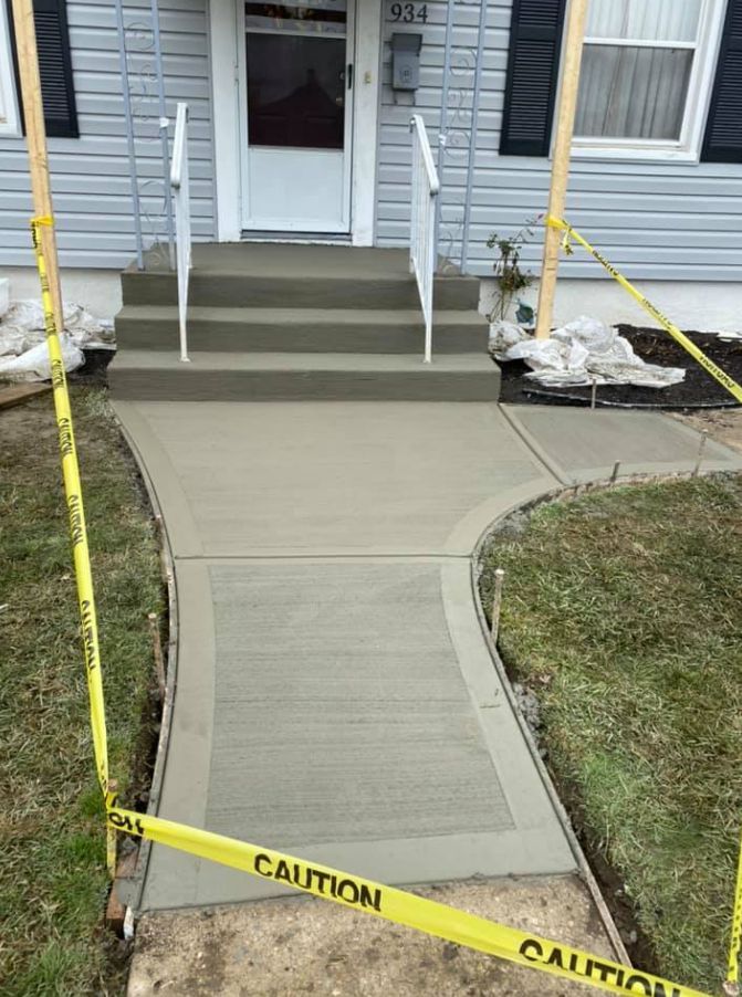A concrete walkway is being built in front of a house