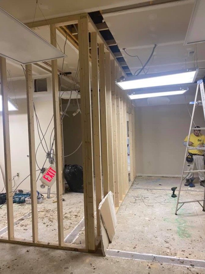 A man is standing on a ladder in a room under construction.