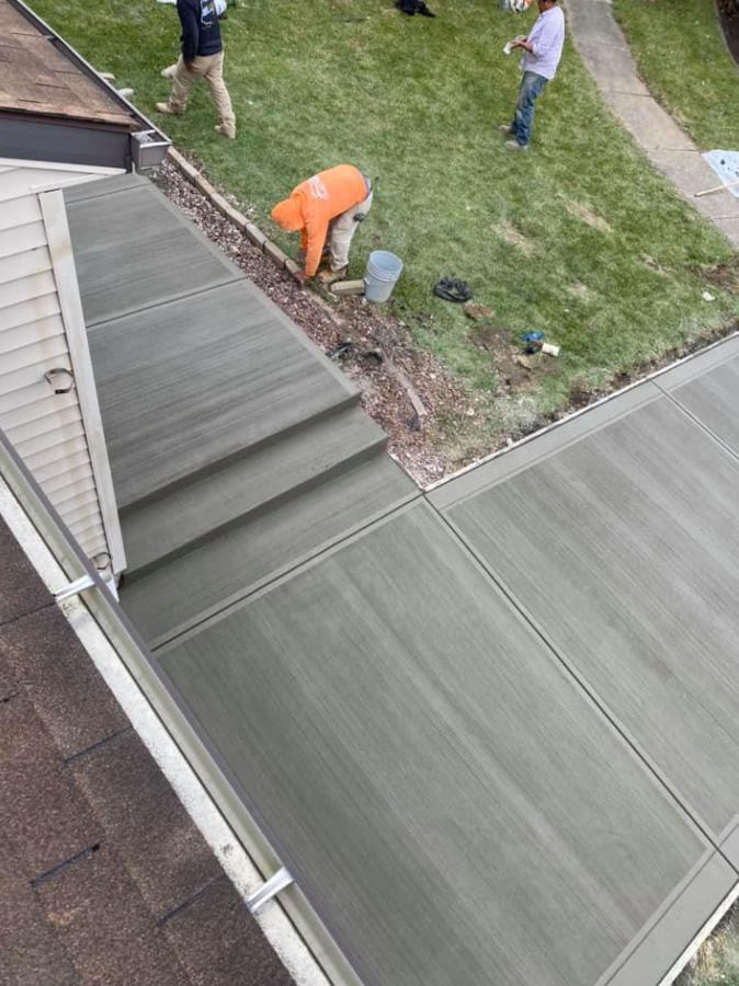A man is working on a concrete walkway in front of a house.