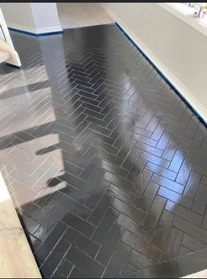 A black herringbone floor is being painted in a room.