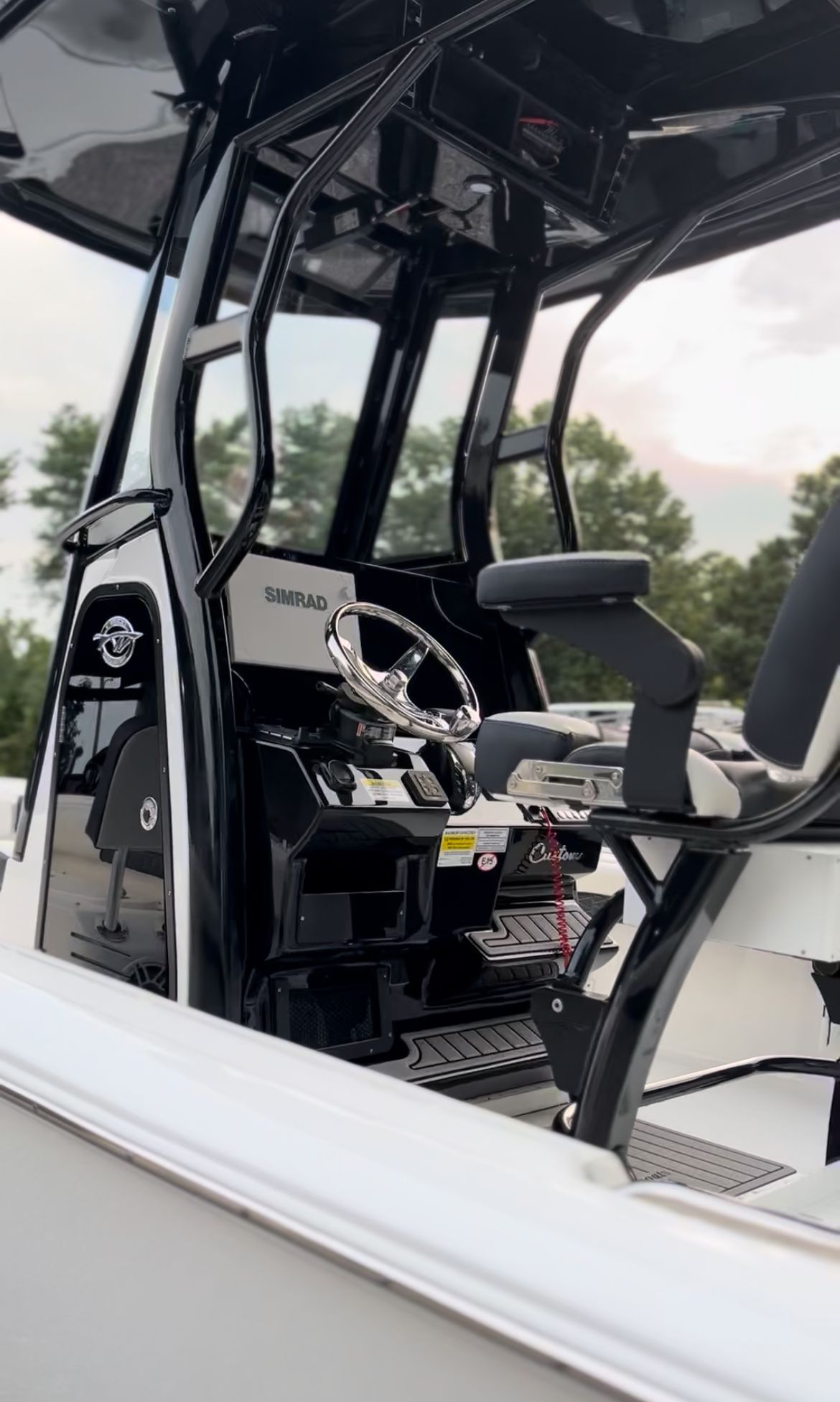 White and black boat interior with a steering wheel and control panel.