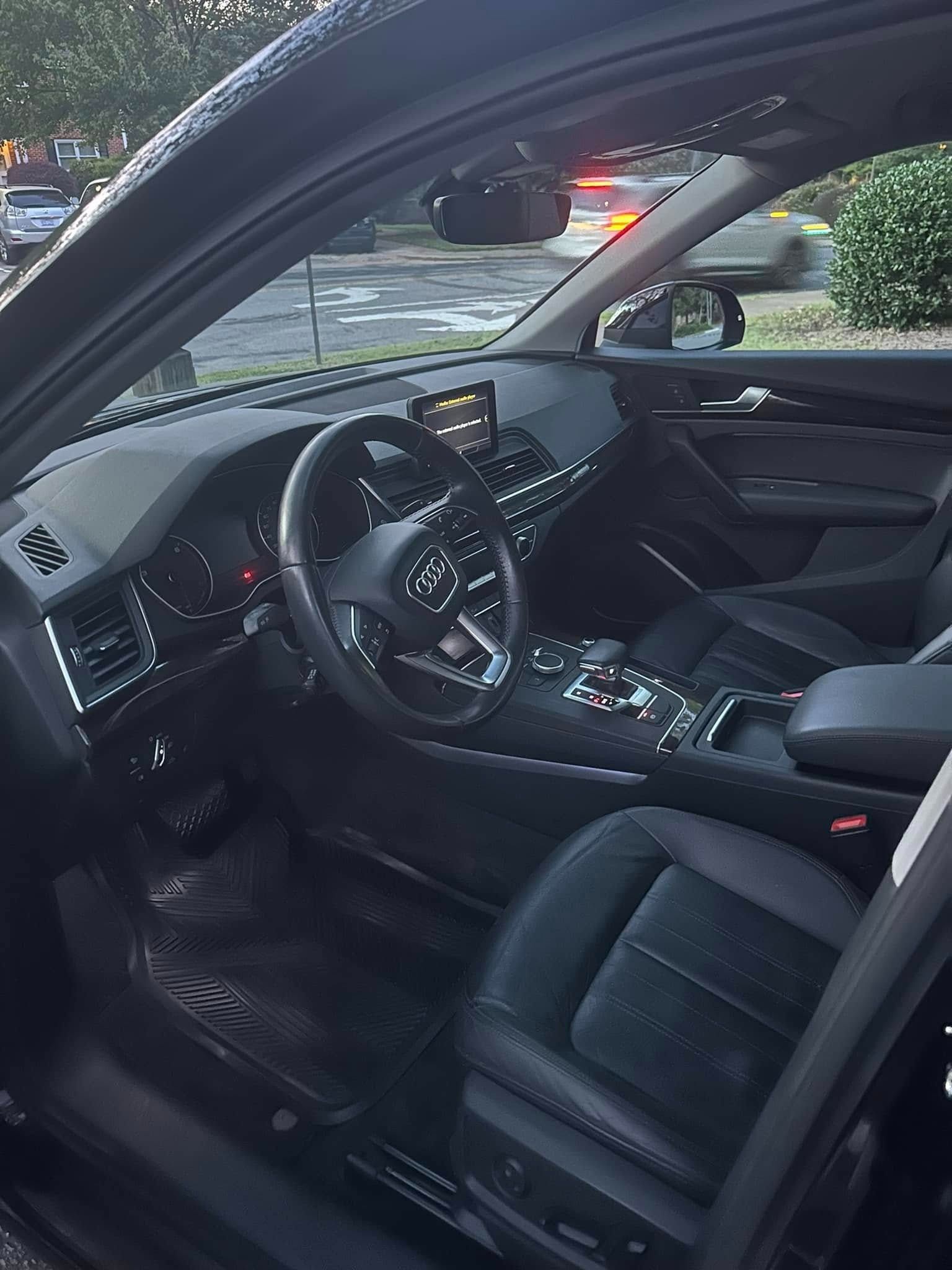 Interior view of a black Audi with black leather seats, dashboard, and a steering wheel.