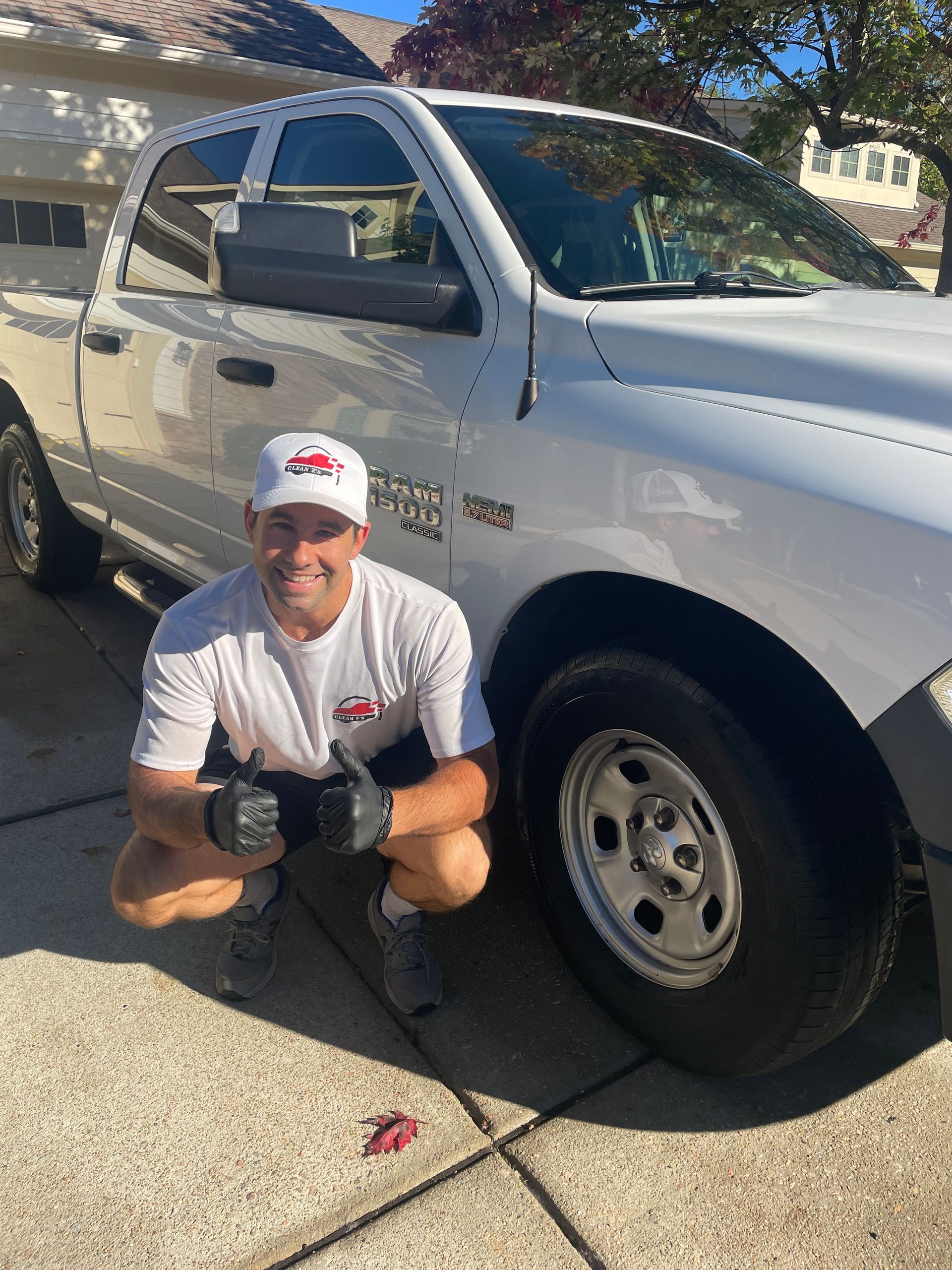 Man standing beside a grey electric pickup truck, smiling, near a sign.