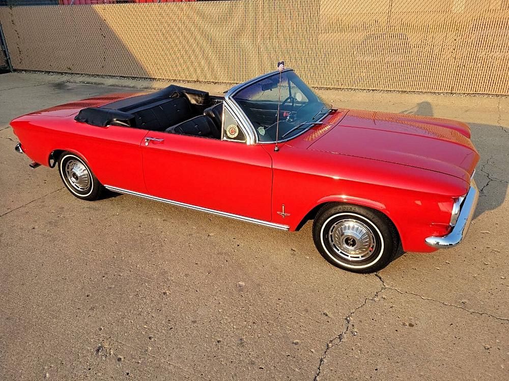 Red vintage convertible car, black interior, parked on a concrete surface.