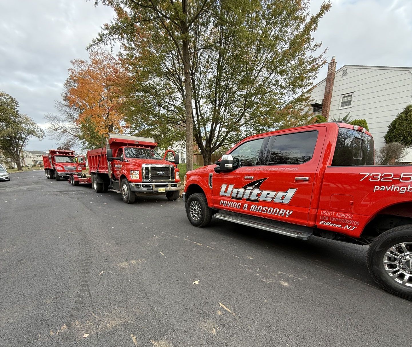 Red United Paving trucks parked on a road