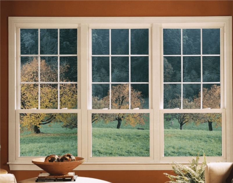 A living room with three windows looking out to a field