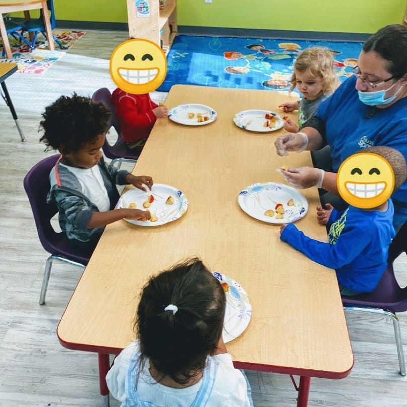A group of children are sitting at a table with plates of food