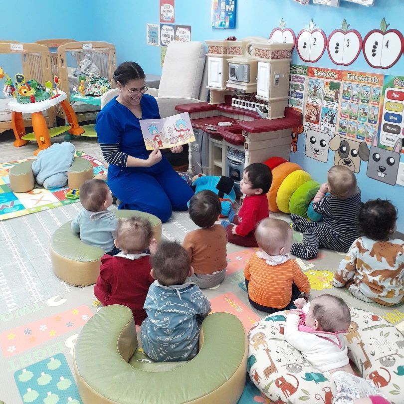 A woman is reading a book to a group of babies