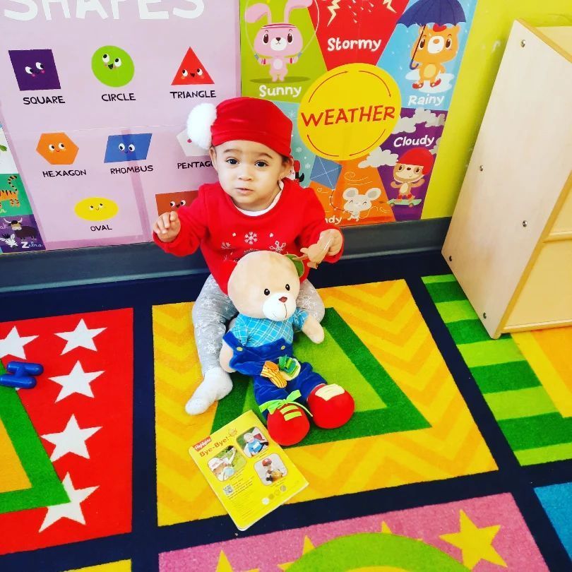 A child is sitting on the floor with a teddy bear and a book that says weather