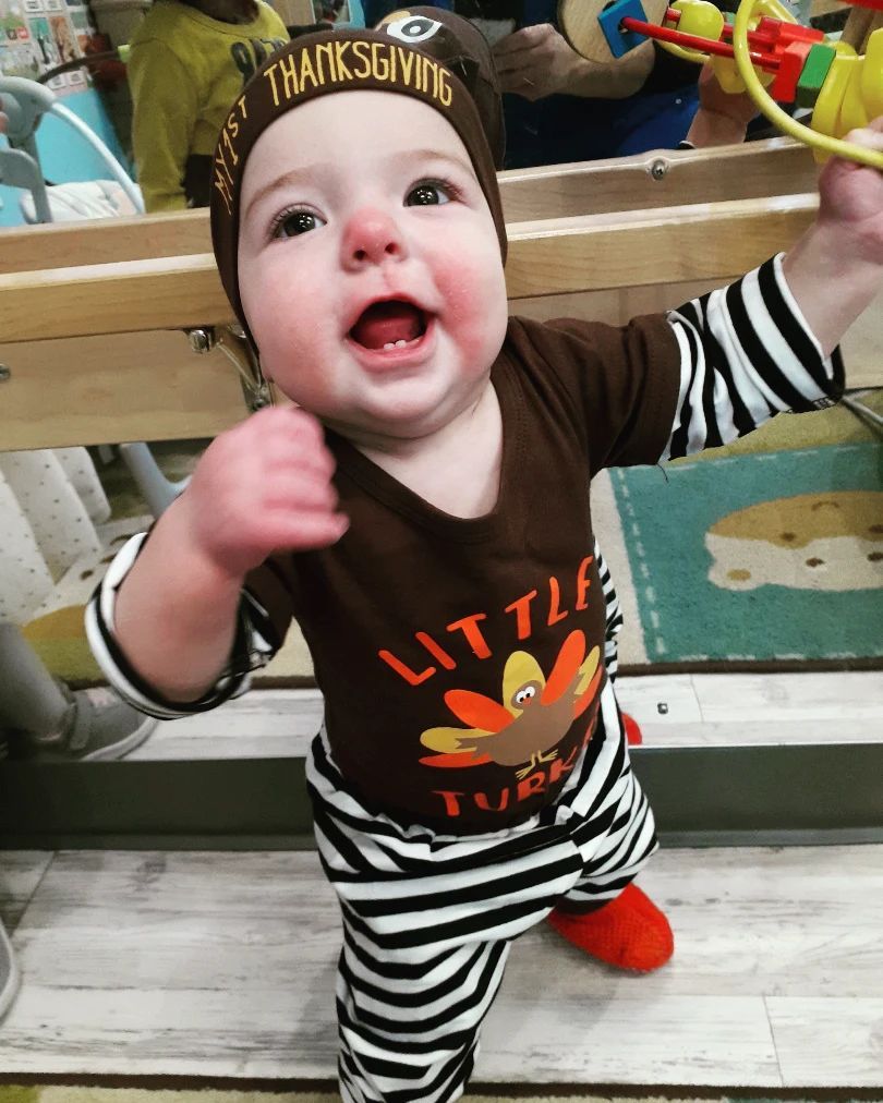 A baby is wearing a little turkey outfit