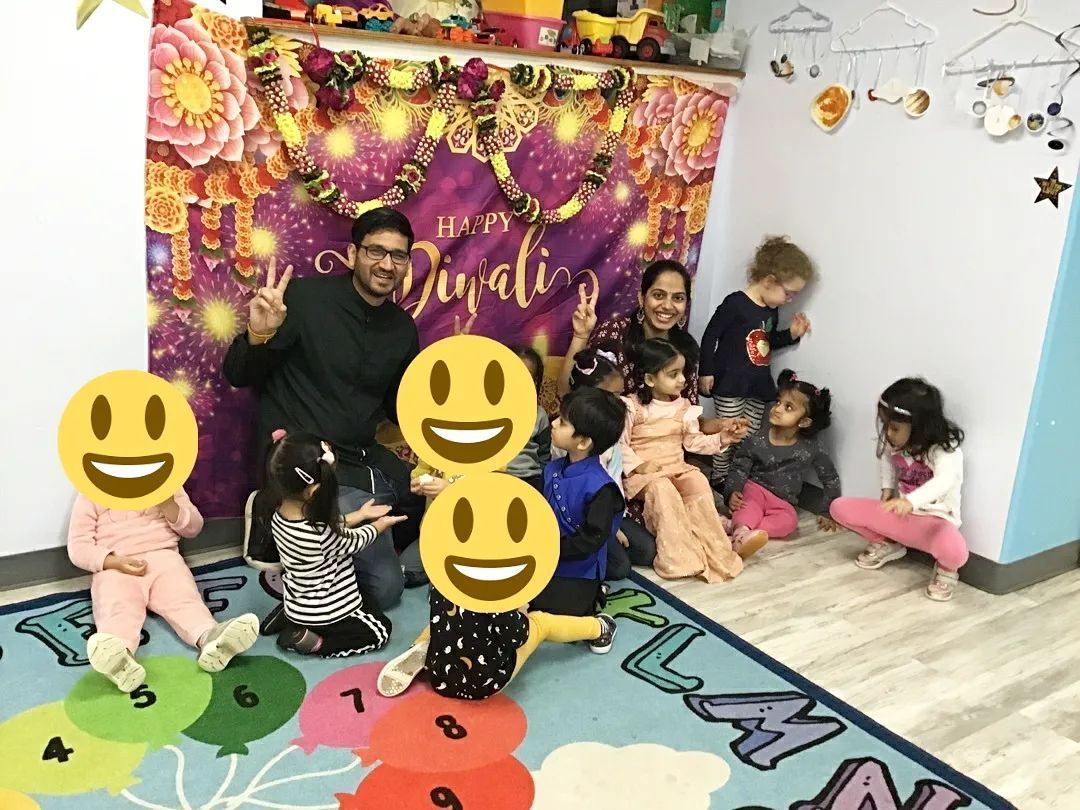 A group of children are sitting on the floor in front of a sign