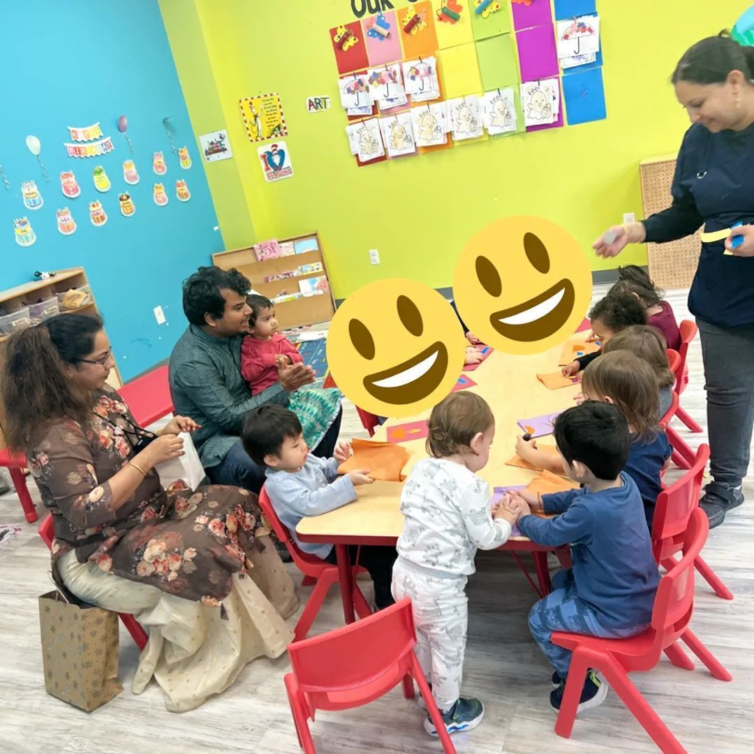 A group of children are sitting around a table with smiley faces on them