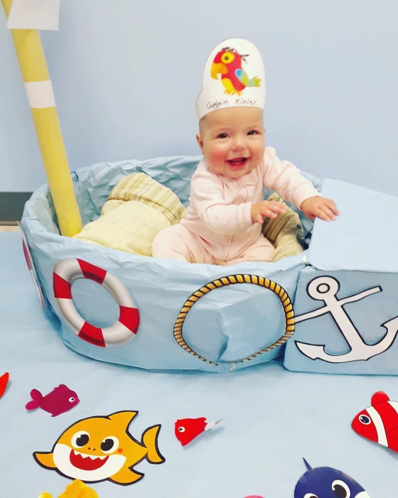 A baby wearing a hat is sitting in a boat