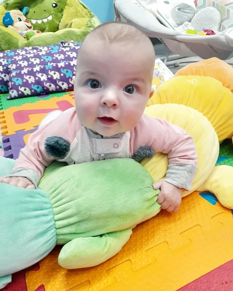 A baby is laying on a mat holding a stuffed animal