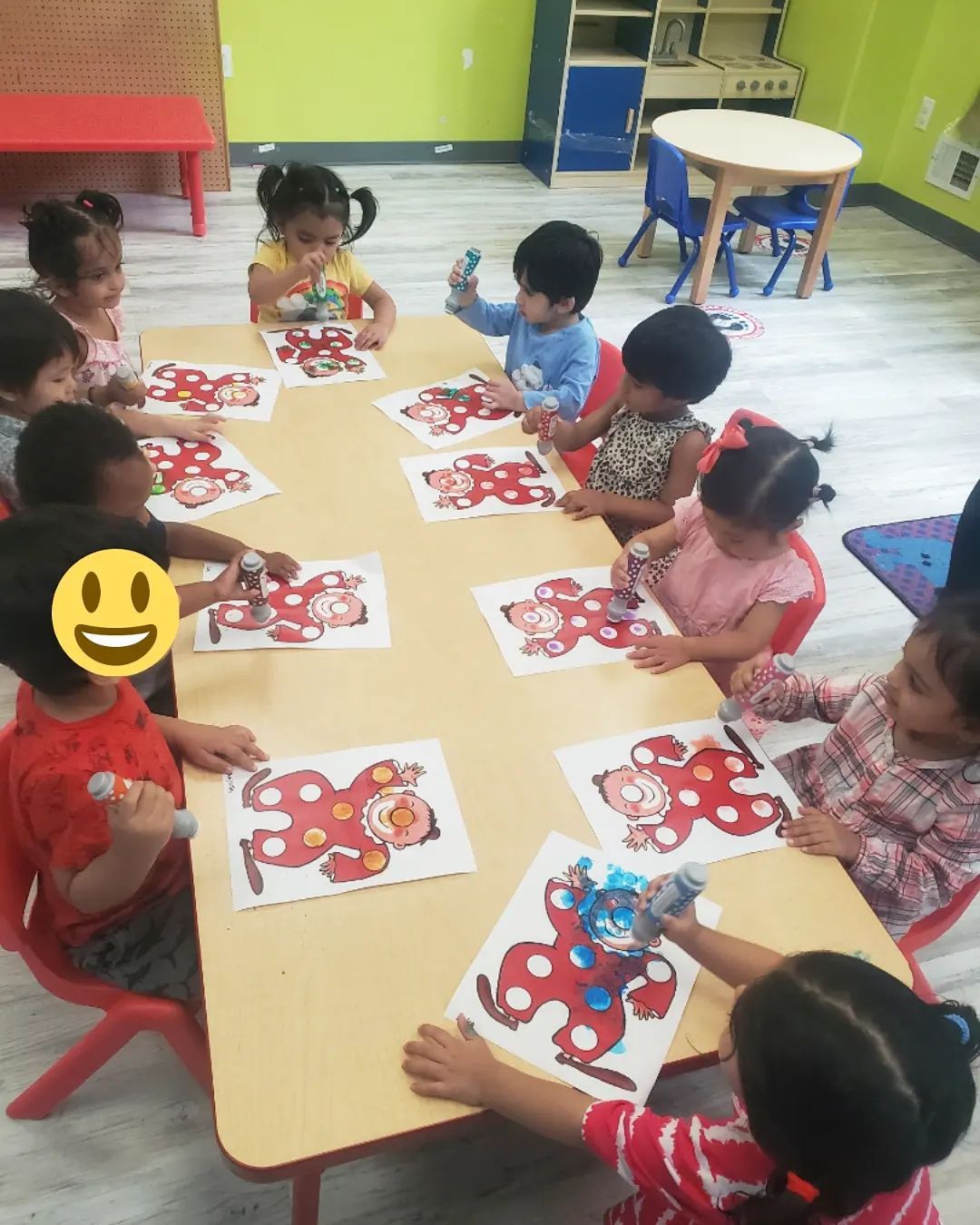 A group of children are sitting at a table painting monkeys