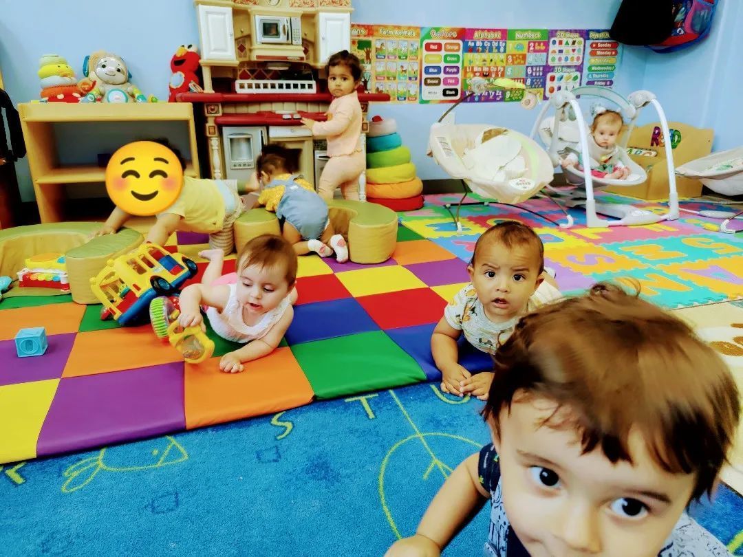 A group of babies are playing on a colorful rug in a play room