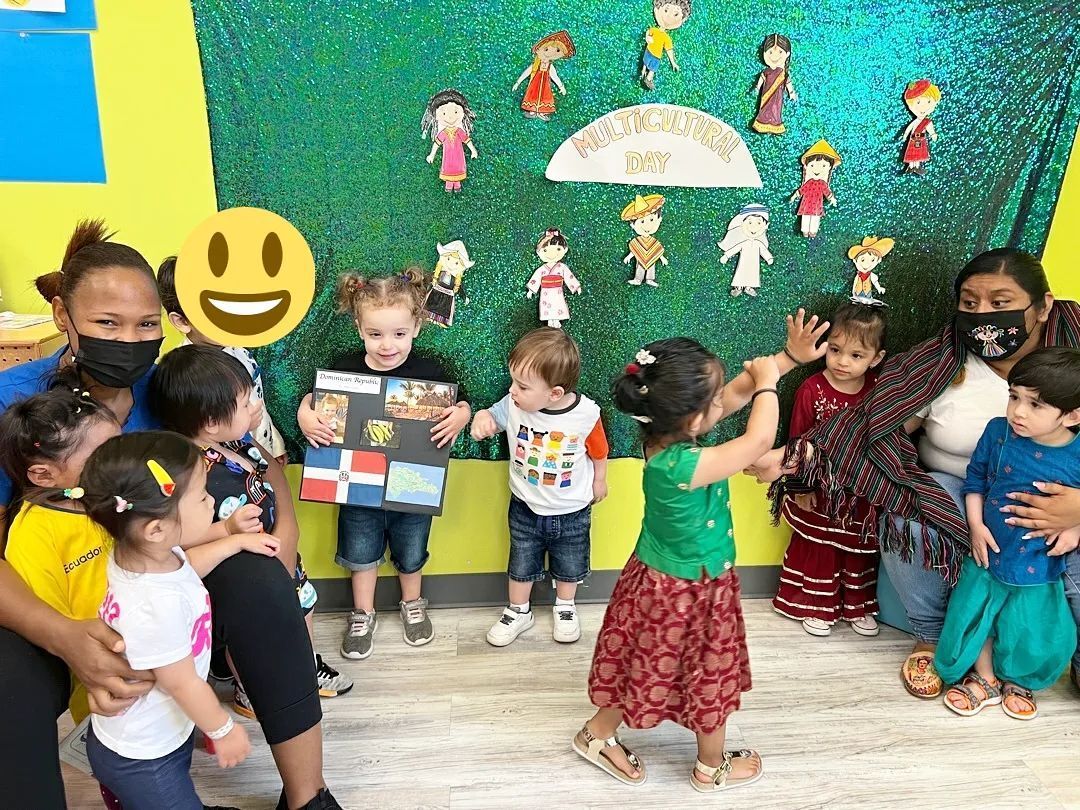 A group of children are dancing in front of a green wall