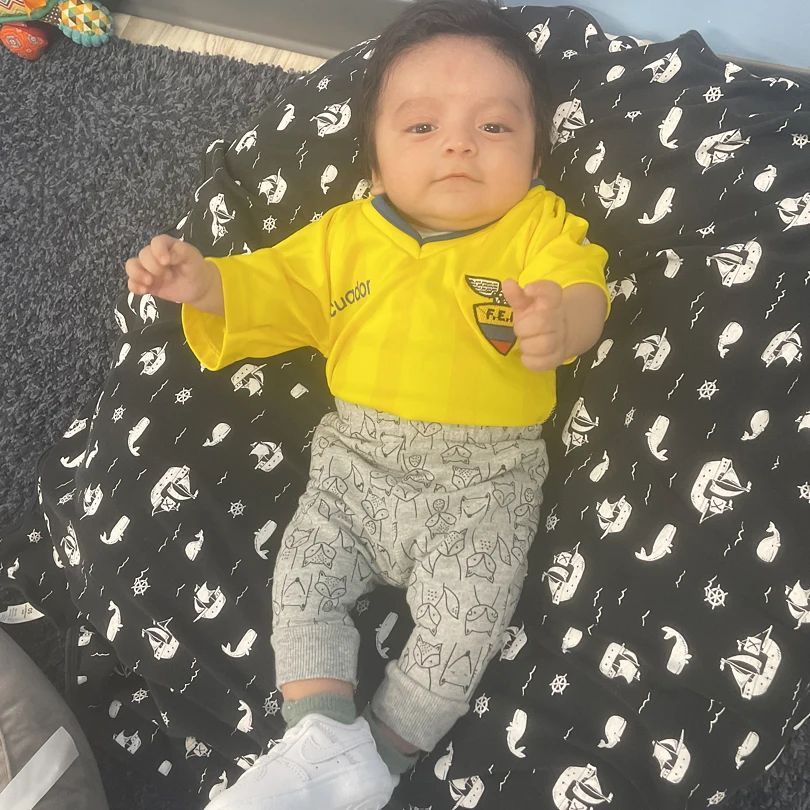 A baby is laying on a black and white blanket