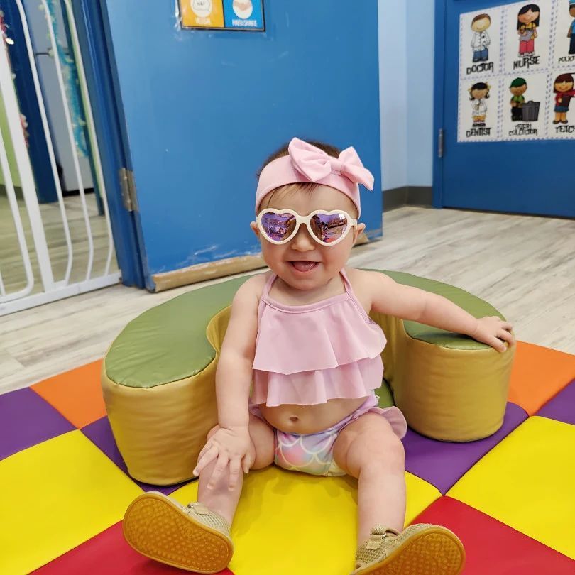 A baby wearing heart shaped sunglasses and a pink headband