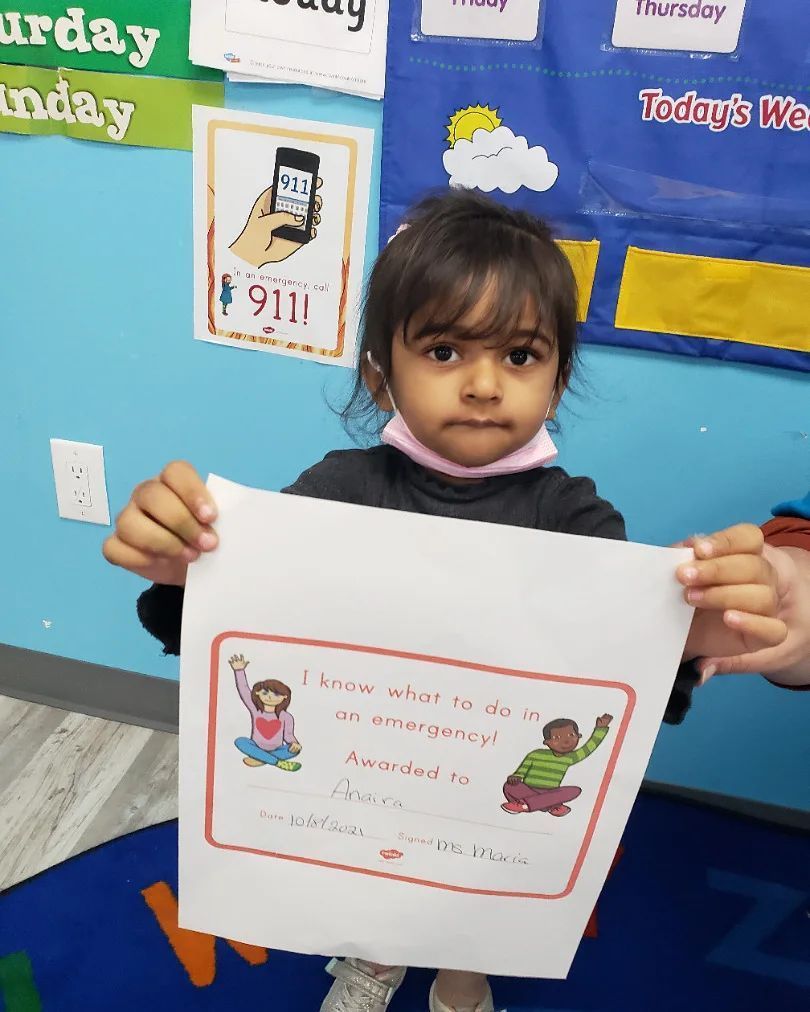 A little girl is holding a piece of paper