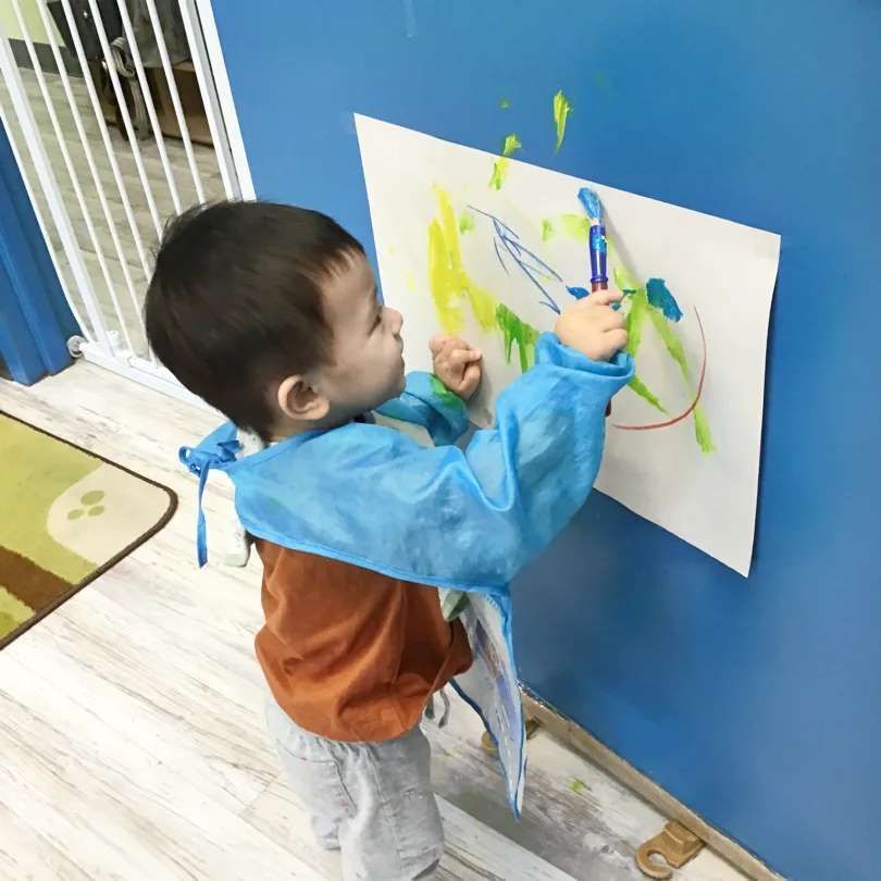 A little boy is drawing on a piece of paper with a marker
