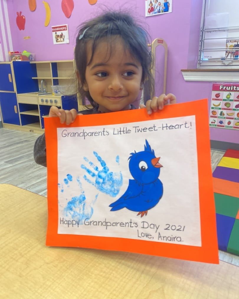A little girl is holding up a card for grandparents day