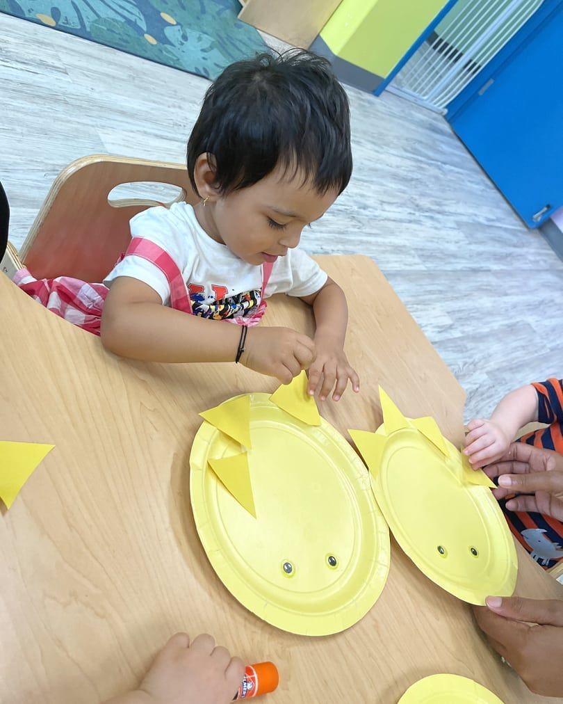 A child is sitting at a table playing with paper plates