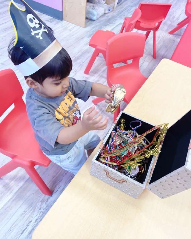 A little boy wearing a pirate hat is playing with a bell