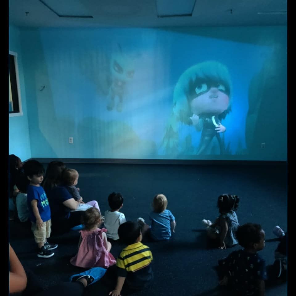 A group of children are watching a cartoon on a large screen