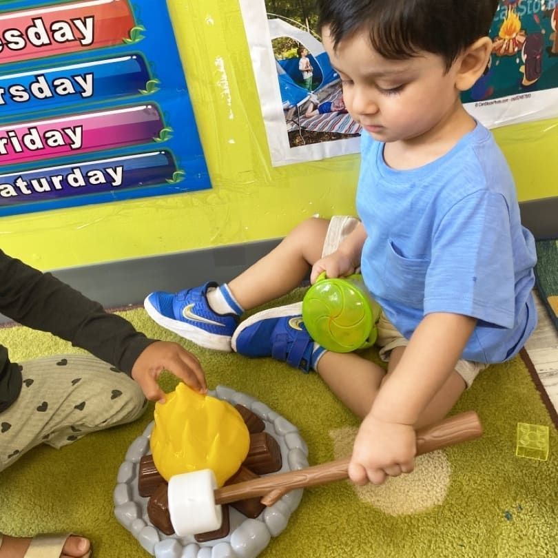 A child is playing with a toy campfire in front of a sign that says saturday