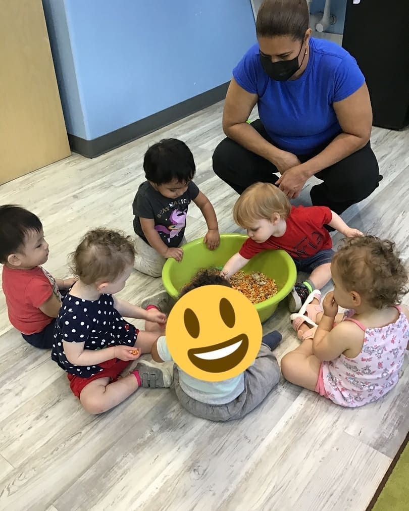A group of children are sitting around a bowl of food