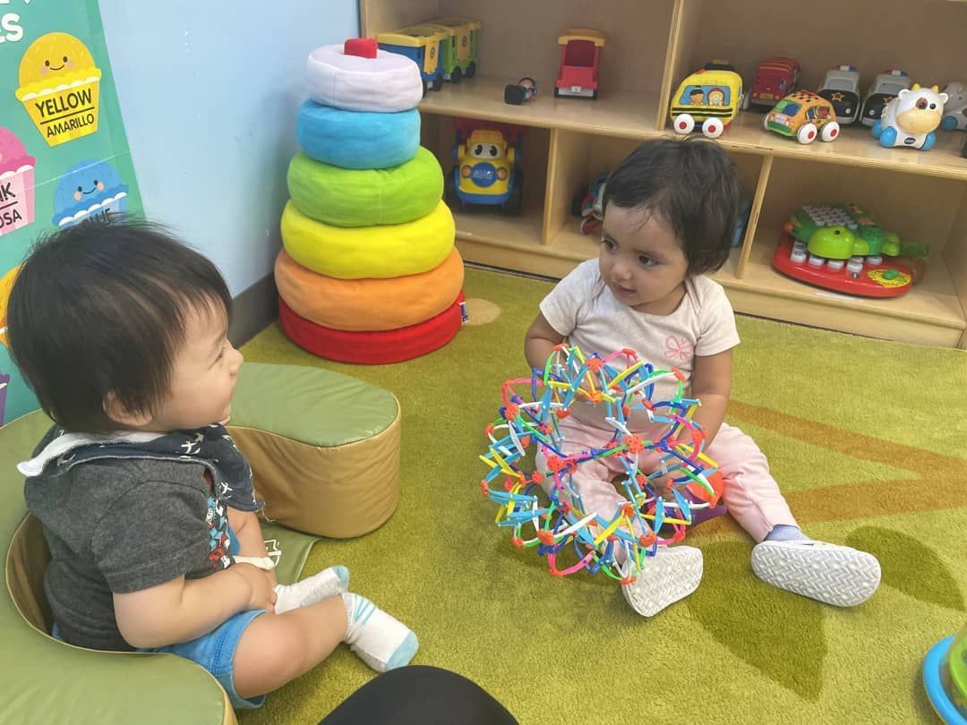 A boy and a girl are sitting on the floor playing with toys