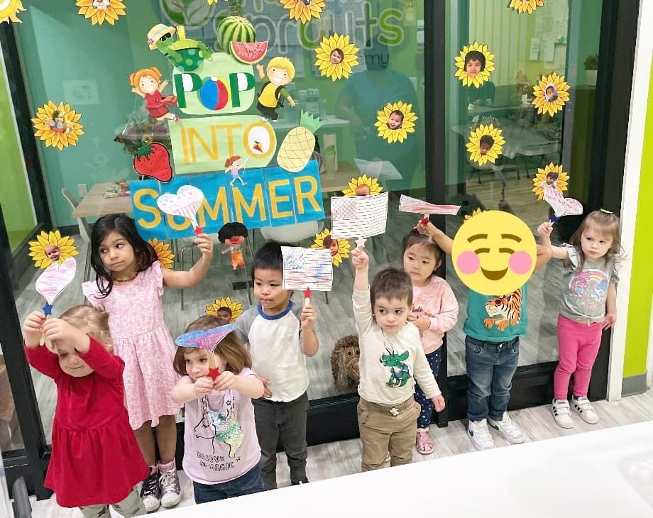 A group of children are standing in front of a window holding signs