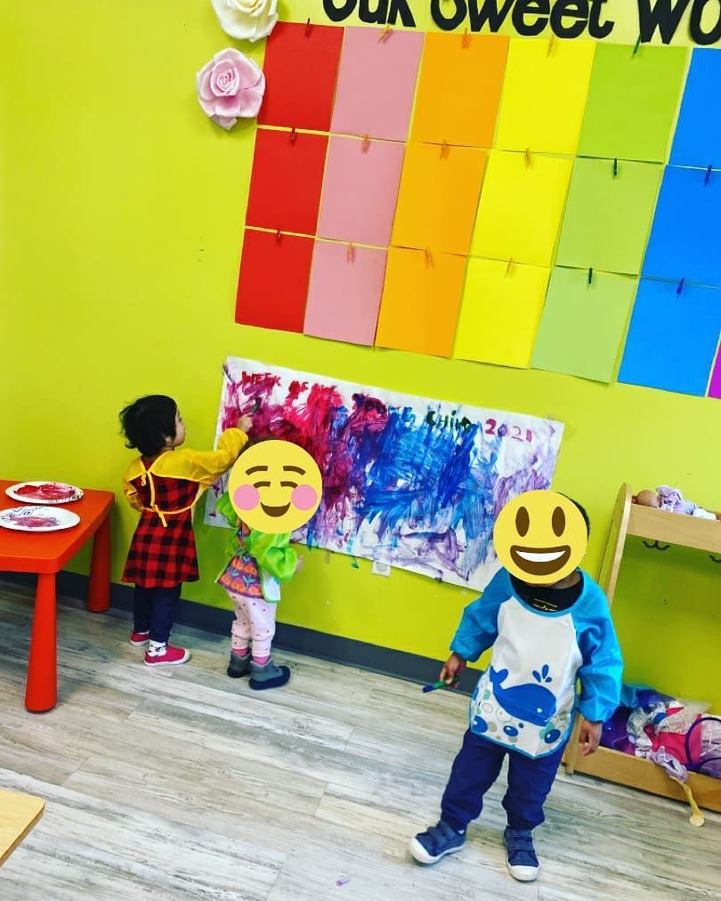 A group of children are standing in front of a rainbow wall
