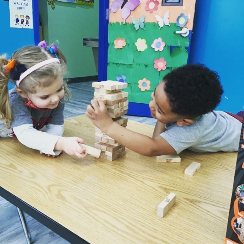 A boy and a girl are playing with wooden blocks on a table