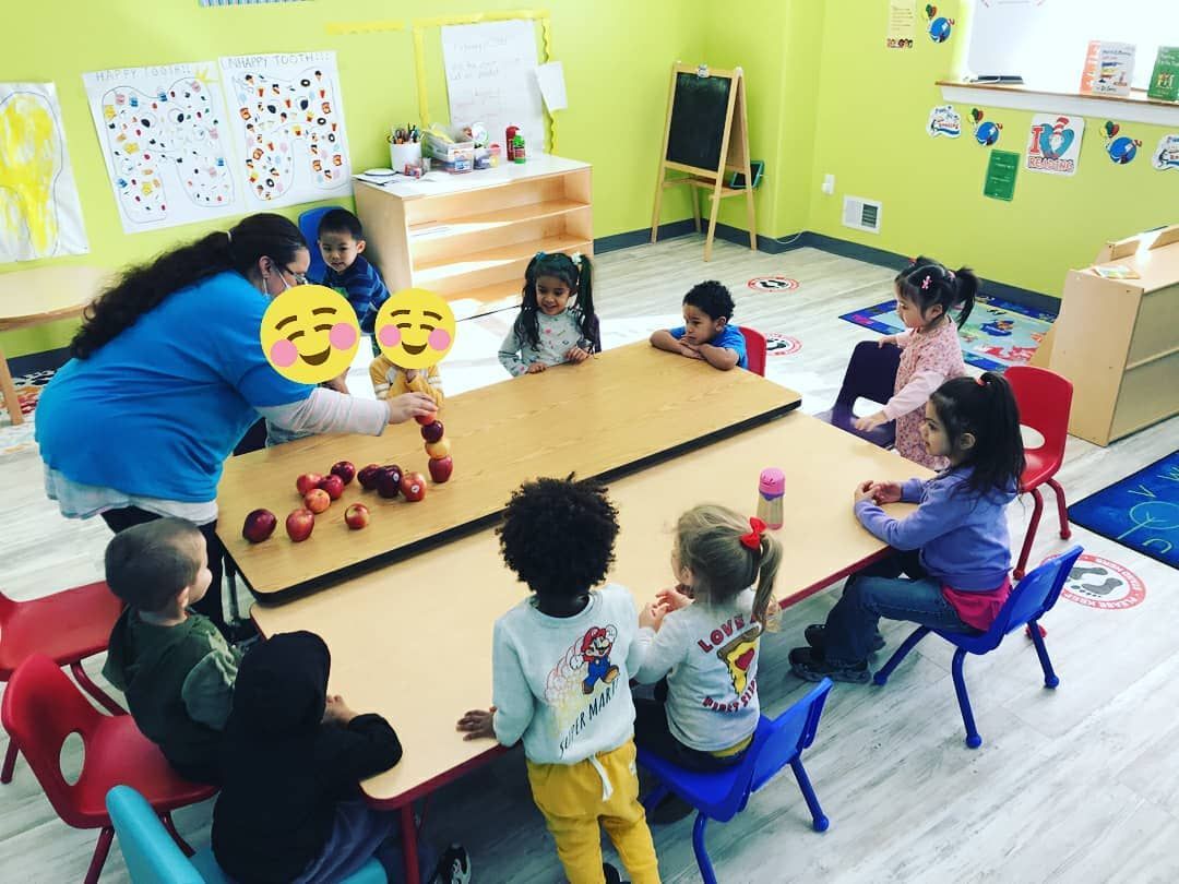 A group of children are sitting around a table in a classroom